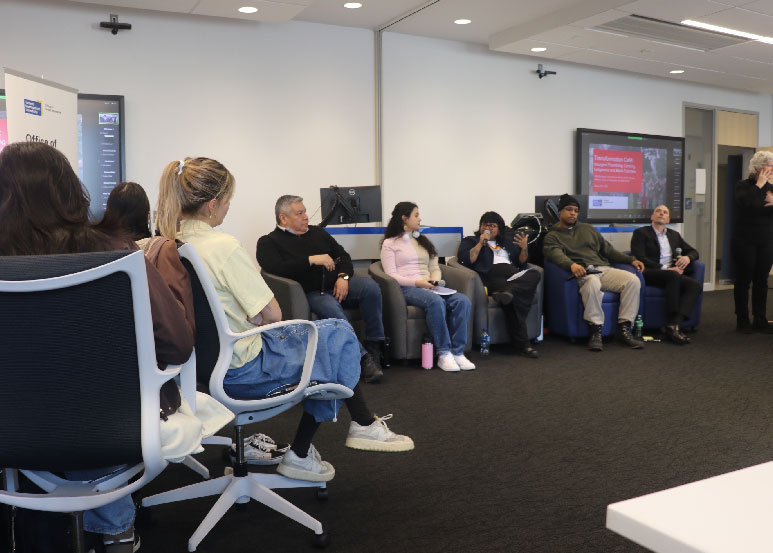 Photo of Transformation Cafe - Insurgent Flourishing: Centring Indigenous and Black Futurities panelists. Attendees look on. ASL interpreter to the side. 